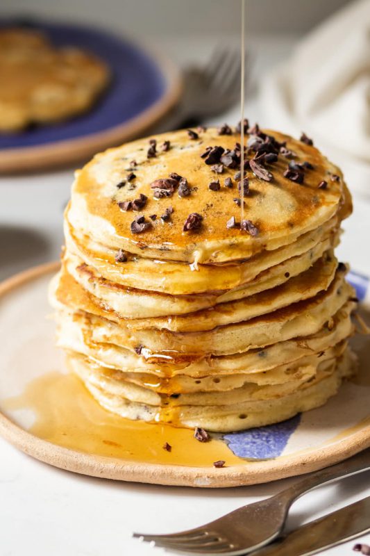 Chocolate Chip Protein Pancakes with syrup being drizzled on top.